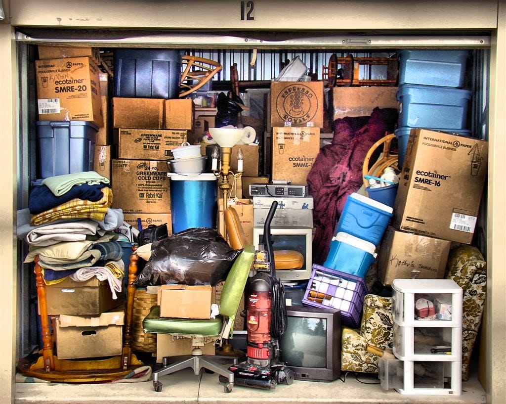 Lots of boxes, chairs and items stuffed inside a garage
