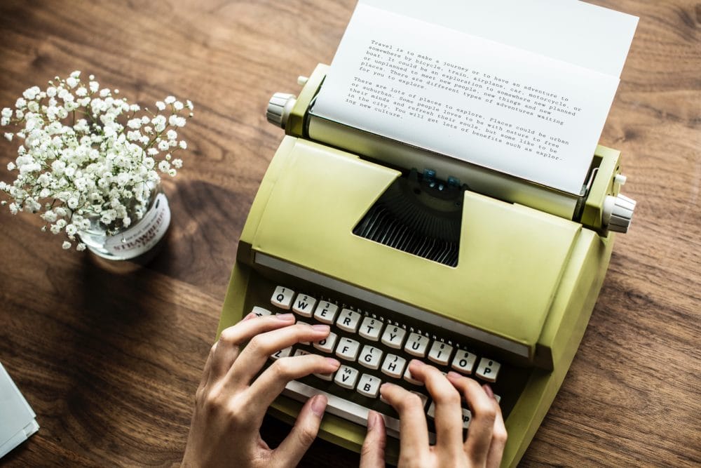 Hands using typewriter on a wooden table